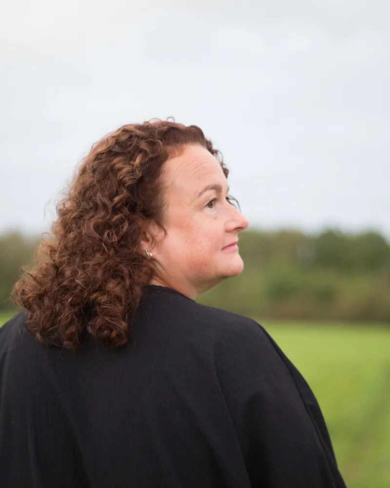 Christiane Wenzel draußen am Feldrand, den Blick in die Ferne gerichtet