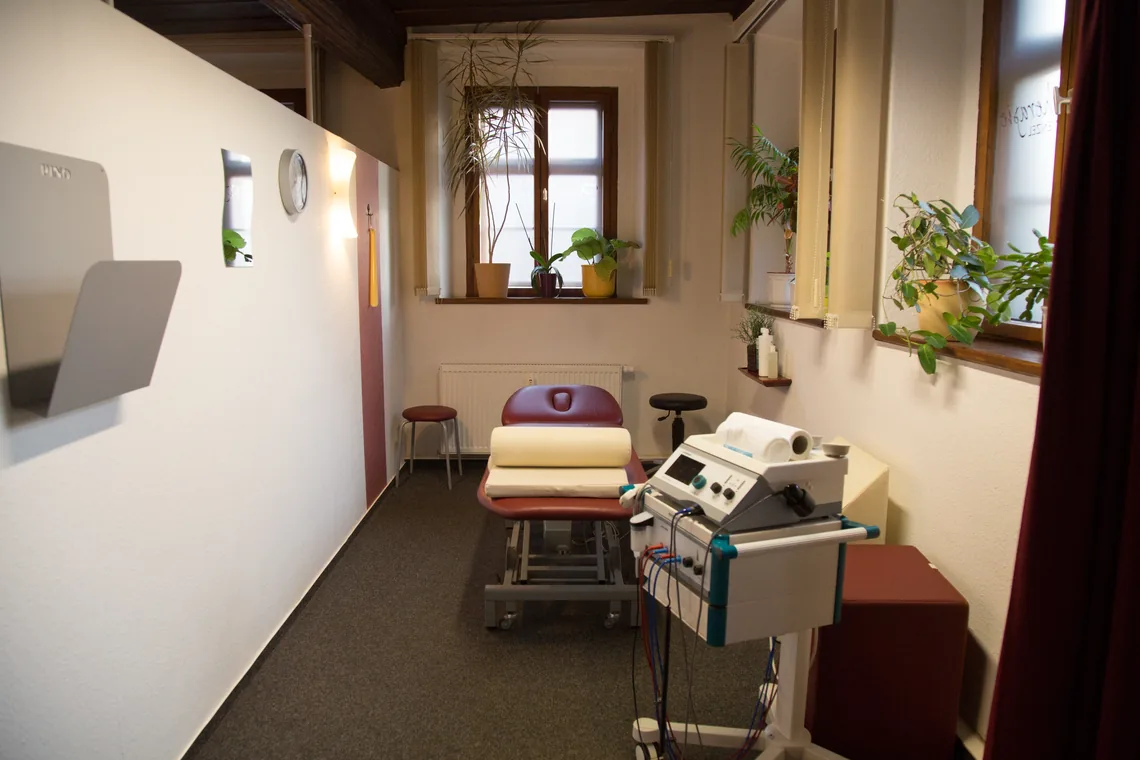 Behandlungskabine mit Liege, Fenster und Elektrotherapiegerät