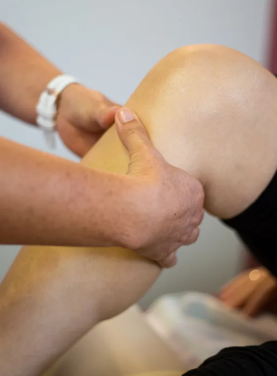 Manuelle Behandlung am Knie einer Patientin
